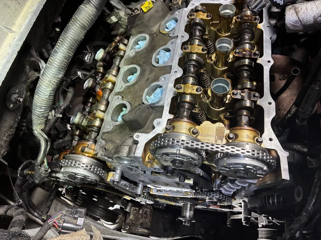 Engine with the valve cover removed showing camshafts and a new timing chain mid-repair